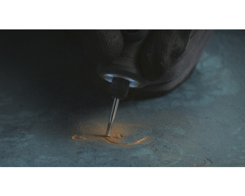 Eine Person graviert mit einem Multifunktionswerkzeug in ein Material.