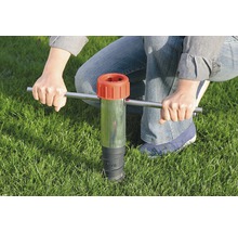 Person verwendet ein Bodeneinschlagwerkzeug im Gras