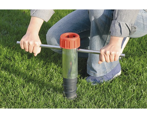 Person verwendet ein Bodeneinschlagwerkzeug im Gras