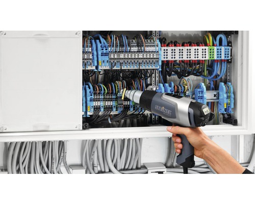 Elektriker arbeitet mit Heißluftpistole an Verteilerkasten
