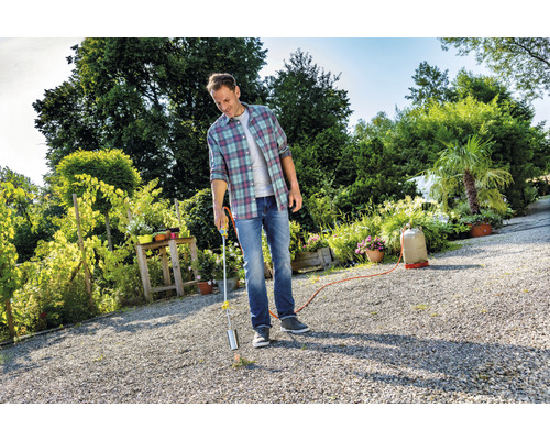 Ein Mann verwendet einen Abflammgerät im Garten zur Unkrautbekämpfung