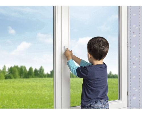 Junge betätigt einen Fenstergriff mit Kindersicherung am weißen Fenster