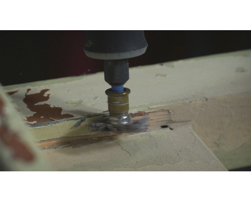 Ein Multifunktionswerkzeug mit Bürstenaufsatz schleift Holz.