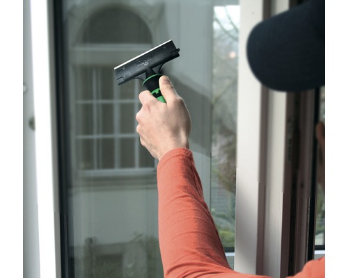 Person reinigt Fenster mit einem Fensterabzieher