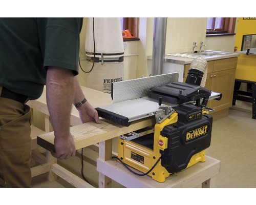 Ein Mann benutzt eine Hobelmaschine, um ein Holzbrett zu bearbeiten.
