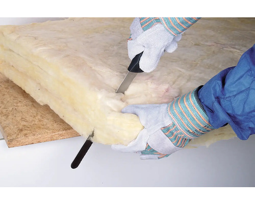 Person schneidet Mineralwolle mit einem Messer zu.