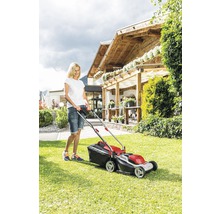Frau bedient Rasenmäher im Garten