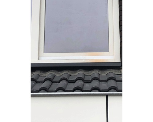 Detailansicht eines Daches mit Ziegeln und einem Fenster.