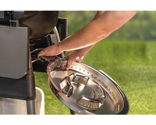 Eine Person setzt eine Edelstahl-Grillpfanne in einen Grill.