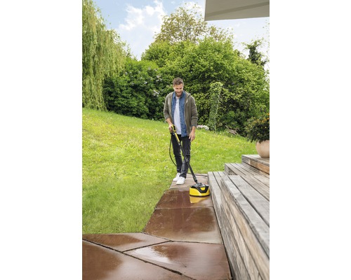 Mann reinigt Terrasse mit Terrassenreiniger