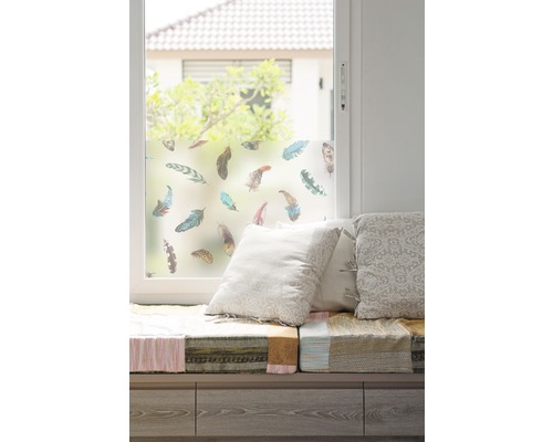 Fenster mit Fensterfolie und Federmotiv, Sitzbank mit Kissen.