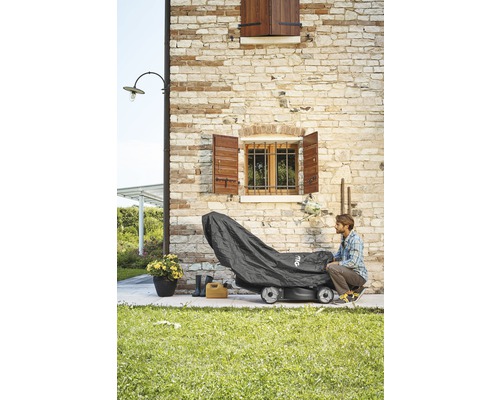 Rasenmäher mit Abdeckung vor einer Steinmauer