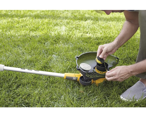 Mann wechselt Fadenspule an einem Rasentrimmer