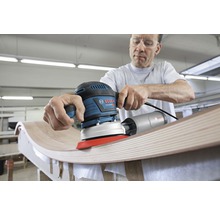 Ein Mann schleift Holz mit einem Bosch Exzenterschleifer.