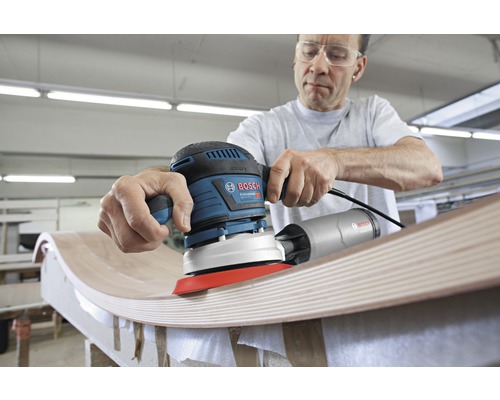 Ein Mann schleift Holz mit einem Bosch Exzenterschleifer.