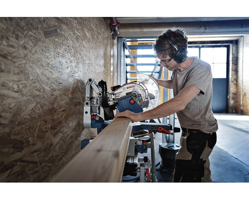 Mann bedient eine Bosch Kapp- und Gehrungssäge zum Zuschneiden eines Holzbretts.