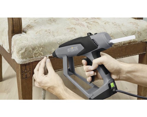 Heißklebepistole beim Anbringen einer Zierleiste an einem Stuhl