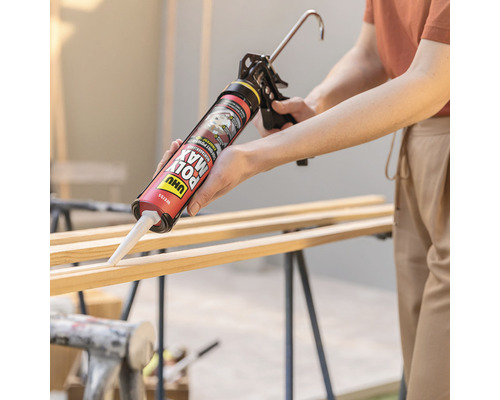 Eine Person verwendet eine Kartuschenpistole, um Klebstoff auf Holzleisten aufzutragen