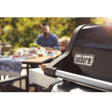 Weber Logo auf einem Grill mit Personen im Hintergrund