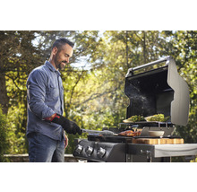 Mann grillt Gemüse und Fleisch auf einem Gasgrill im Freien