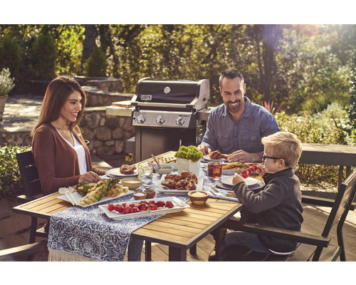 Familie grillt im Freien mit einem Gasgrill und genießt das Essen am Holztisch