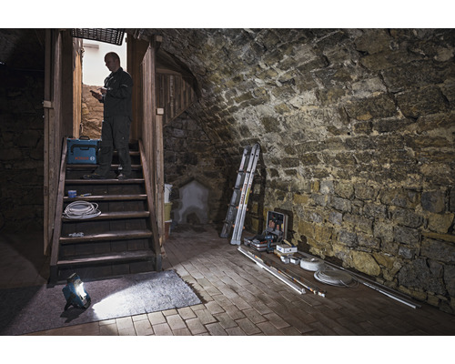 Kellerraum mit Steintreppe, Arbeitsleuchte, Werkzeugkoffer und Handwerker