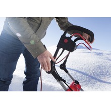 Eine Person bedient eine Schneefräse im Schnee.