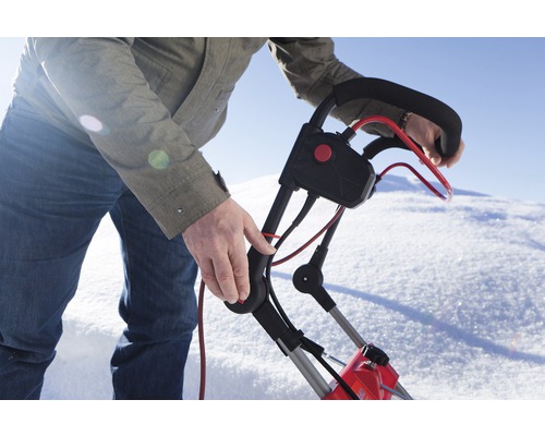 Eine Person bedient eine Schneefräse im Schnee.