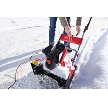 Eine Person bedient eine Schneefräse auf einer verschneiten Oberfläche.