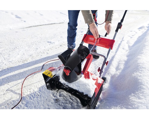 Eine Person bedient eine Schneefräse auf einer verschneiten Oberfläche.