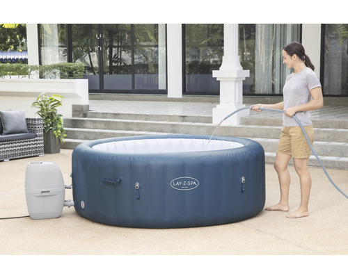 Aufblasbarer Lay-Z-Spa Whirlpool im Garten mit Frau beim Befüllen mit Wasser.