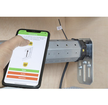 Smartphone mit App zur Rollladensteuerung neben einem Rollladenmotor.