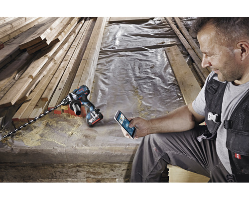 Akku-Bohrschrauber mit Holzbohrer und Handwerker mit Smartphone