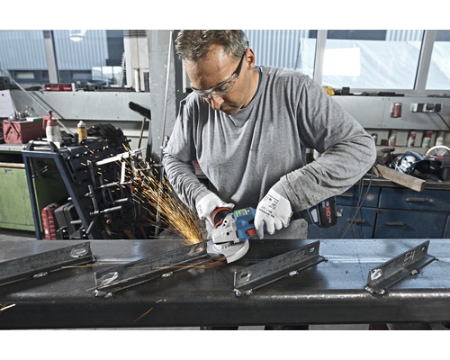 Mann schleift Metall mit einem Winkelschleifer in einer Werkstatt