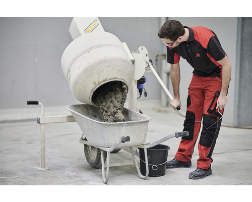 Ein Mann leert Beton aus einem Betonmischer in eine Schubkarre.