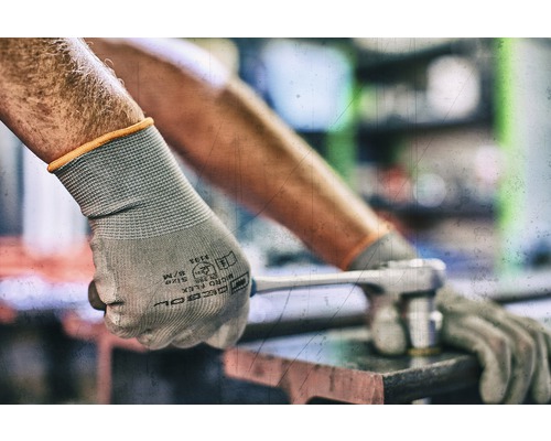 Eine Person mit Schutzhandschuhen benutzt einen Schraubenschlüssel.