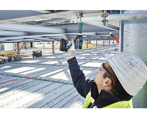 Ein Bauarbeiter befestigt ein Rohr mit einem Akku-Schlagschrauber auf einer Baustelle.