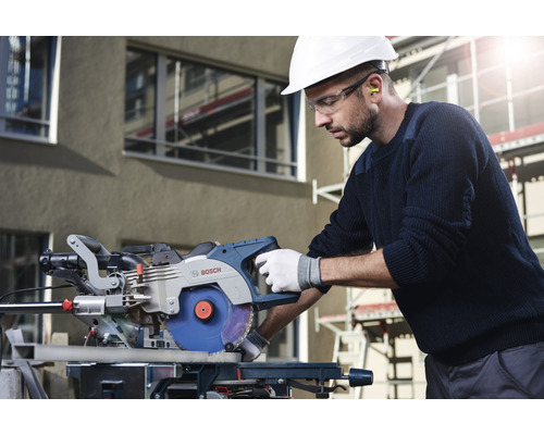 Ein Mann mit Schutzhelm und Schutzbrille bedient eine Bosch Kappsäge.