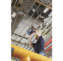 Ein Mann mit Schutzhelm schneidet ein Rohr mit einer Rohrsäge