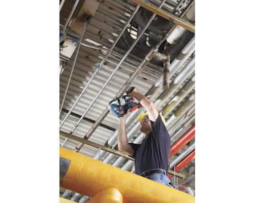 Ein Mann mit Schutzhelm schneidet ein Rohr mit einer Rohrsäge