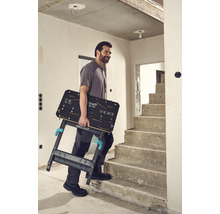 Mann trägt Wolfcraft Logo Klapptisch die Treppe hoch