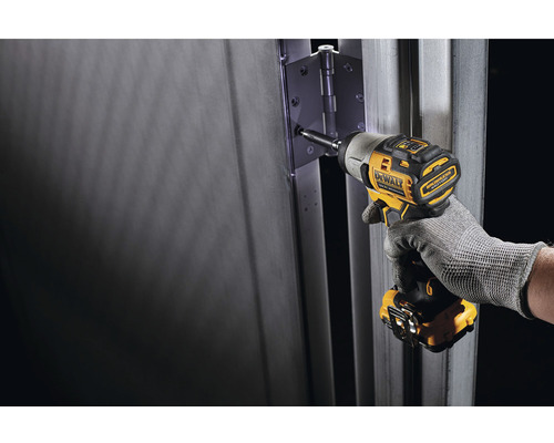 Ein Akku-Schlagschrauber der Marke DeWalt wird verwendet, um ein Türscharnier an einer Tür zu befestigen.