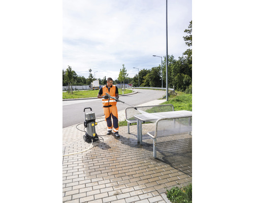 Eine Person benutzt einen Hochdruckreiniger, um eine Sitzgruppe im Freien zu reinigen.
