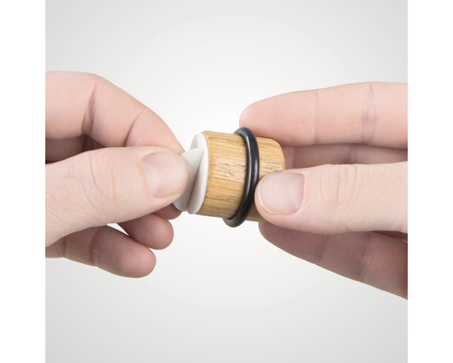 Weinstopfen aus Holz mit Gummidichtung wird von Händen gehalten