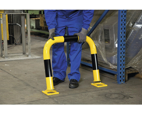 Eine Person installiert einen Anfahrschutzbügel in einem Lager.