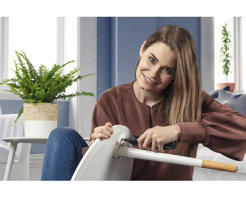 Eine Frau montiert mit einem Akkuschrauber einen Stuhl.