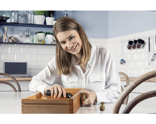 Frau montiert Schubladengriff in Ananasform an Holzschublade in Küche