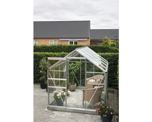 Gewächshaus mit geöffneter Tür und Sitzgruppe im Garten