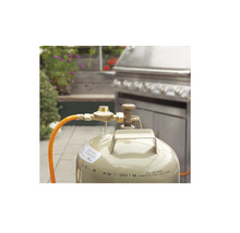 Gasflasche mit Druckminderer und Gasschlauch vor einem Grill