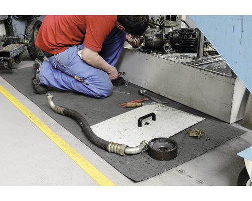 Arbeiter kniet auf einer Auffangmatte während einer Reparatur.